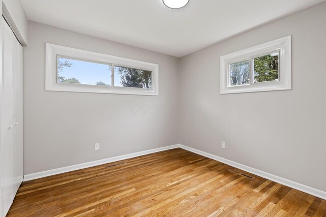 1001 S Harris Ave, Columbus, OH 43204 - unfurnished bedroom with multiple windows, a closet, baseboards, and light wood-style flooring