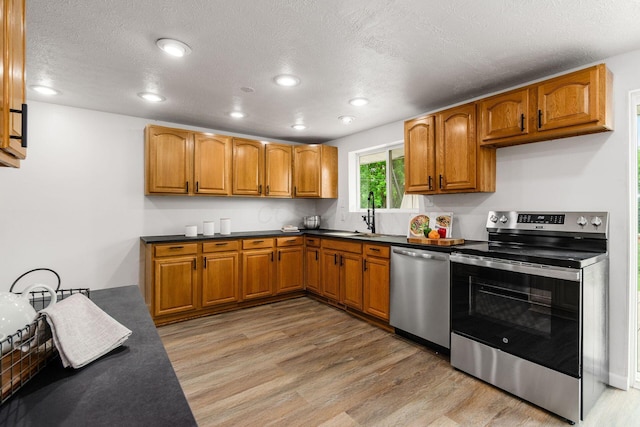 3944 Ardath Rd, Columbus, OH 43228 - kitchen with appliances with stainless steel finishes, a sink, light wood-style floors, dark countertops, and brown cabinets