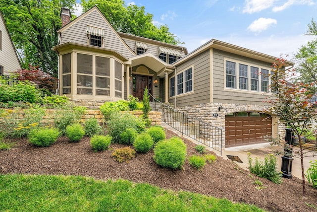 137 E Torrence Rd, Columbus, OH 43214 - view of front facade featuring an attached garage, stone siding, a chimney, a sunroom, and concrete driveway