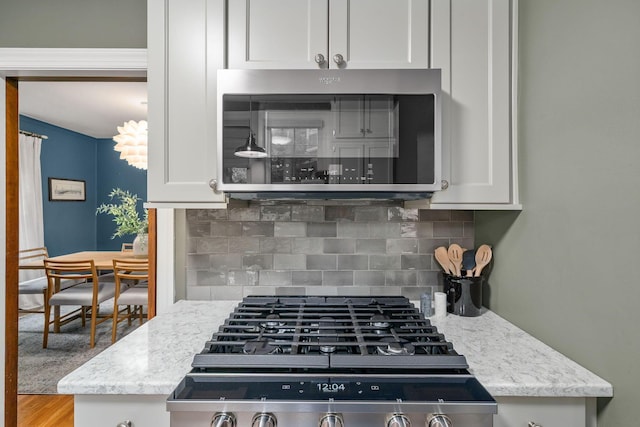 137 E Torrence Rd, Columbus, OH 43214 - kitchen with white cabinets, tasteful backsplash, stainless steel microwave, and light stone countertops