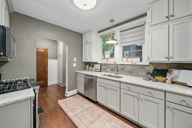 137 E Torrence Rd, Columbus, OH 43214 - kitchen featuring a sink, stainless steel appliances, arched walkways, decorative backsplash, and baseboards
