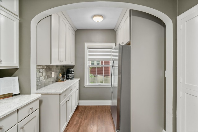 137 E Torrence Rd, Columbus, OH 43214 - kitchen featuring freestanding refrigerator, arched walkways, dark wood-style floors, baseboards, and decorative backsplash