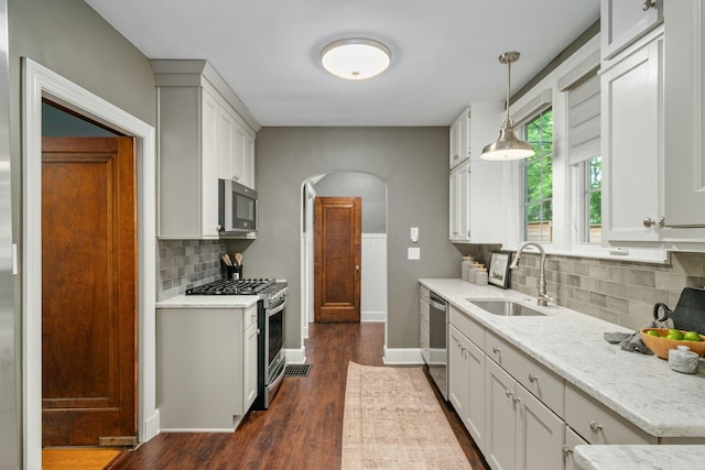 137 E Torrence Rd, Columbus, OH 43214 - kitchen with stainless steel appliances, a sink, arched walkways, decorative backsplash, and baseboards