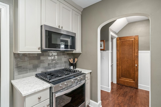 137 E Torrence Rd, Columbus, OH 43214 - kitchen featuring appliances with stainless steel finishes, decorative backsplash, arched walkways, dark wood-type flooring, and white cabinets