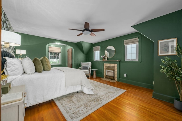 137 E Torrence Rd, Columbus, OH 43214 - bedroom with wood finished floors, arched walkways, baseboards, a fireplace with flush hearth, and a ceiling fan