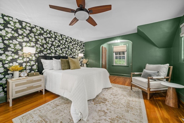 137 E Torrence Rd, Columbus, OH 43214 - bedroom with arched walkways, wood finished floors, an accent wall, a ceiling fan, and baseboards