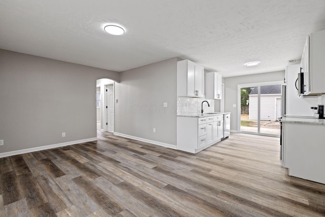 191 Saint Christopher Ln, Columbus, OH 43213 - kitchen with a sink, arched walkways, baseboards, light wood-style flooring, and white cabinets