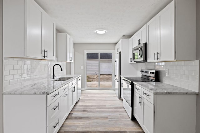 191 Saint Christopher Ln, Columbus, OH 43213 - kitchen featuring appliances with stainless steel finishes, a sink, light wood finished floors, a textured ceiling, and white cabinets