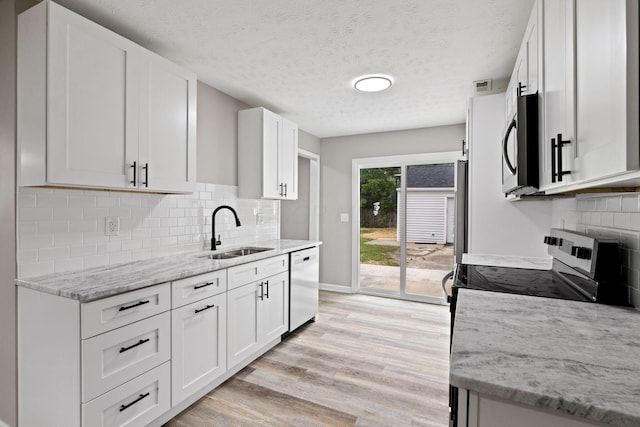 191 Saint Christopher Ln, Columbus, OH 43213 - kitchen with a sink, appliances with stainless steel finishes, light wood-style floors, white cabinetry, and light stone countertops