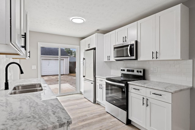 191 Saint Christopher Ln, Columbus, OH 43213 - kitchen featuring stainless steel appliances, a sink, light wood-style floors, tasteful backsplash, and white cabinetry