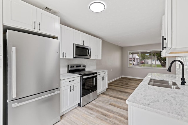191 Saint Christopher Ln, Columbus, OH 43213 - kitchen featuring appliances with stainless steel finishes, a sink, tasteful backsplash, light wood-style floors, and white cabinets
