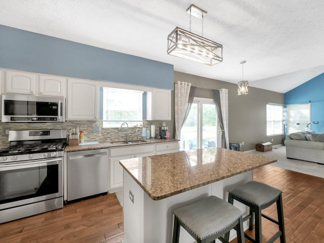 6048 Trent Ct, Lewis Center, OH 43035 - kitchen featuring stainless steel appliances, a sink, wood finished floors, open floor plan, and lofted ceiling
