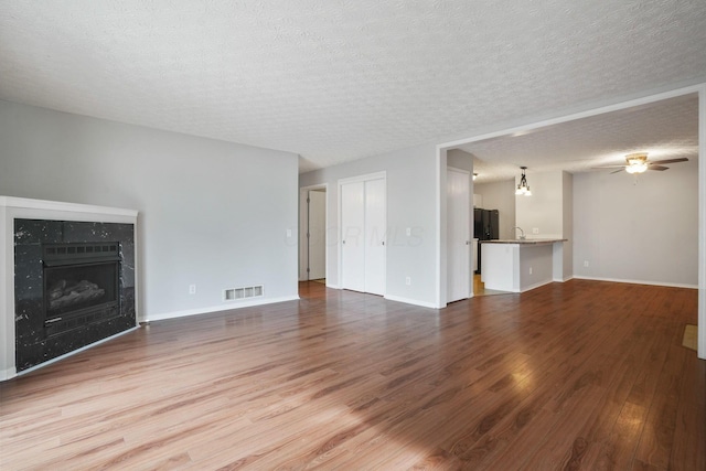 4655 Parrau Dr Unit 66A, Columbus, OH 43228 - unfurnished living room featuring wood finished floors, a fireplace, a textured ceiling, a ceiling fan, and baseboards