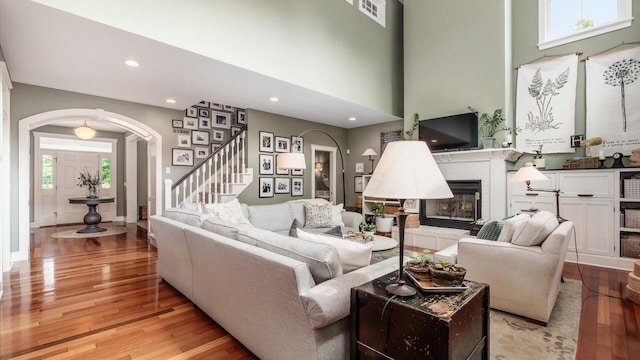 122 Boulder Ct, Granville, OH 43023 - living room with arched walkways, wood finished floors, a tiled fireplace, stairs, and recessed lighting