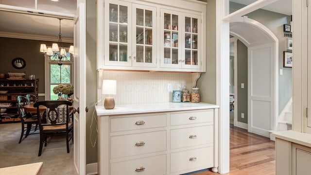 122 Boulder Ct, Granville, OH 43023 - kitchen with light countertops, glass insert cabinets, a chandelier, arched walkways, and crown molding