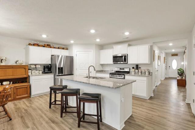 351 Trinity Way W, Newark, OH 43055 - kitchen with appliances with stainless steel finishes, a sink, a kitchen breakfast bar, light wood finished floors, and a kitchen island with sink