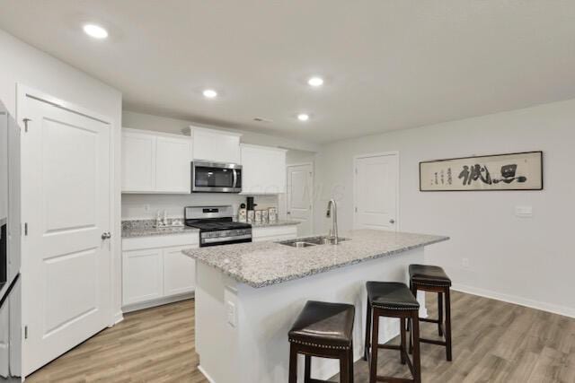 351 Trinity Way W, Newark, OH 43055 - kitchen featuring stainless steel appliances, a sink, a breakfast bar, light wood finished floors, and an island with sink