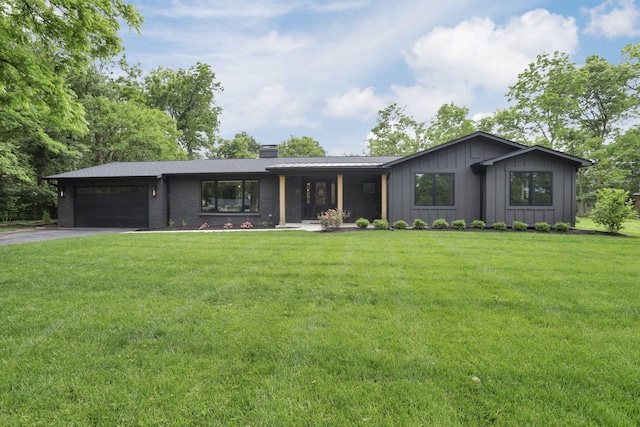 29 Pocono Rd, Columbus, OH 43235 - view of front of home with a chimney, asphalt driveway, a garage, a front yard, and board and batten siding