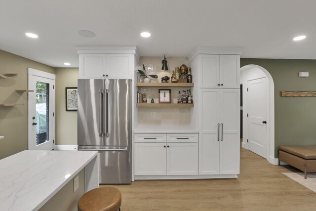 29 Pocono Rd, Columbus, OH 43235 - kitchen with high end fridge, light wood-type flooring, arched walkways, white cabinetry, and recessed lighting