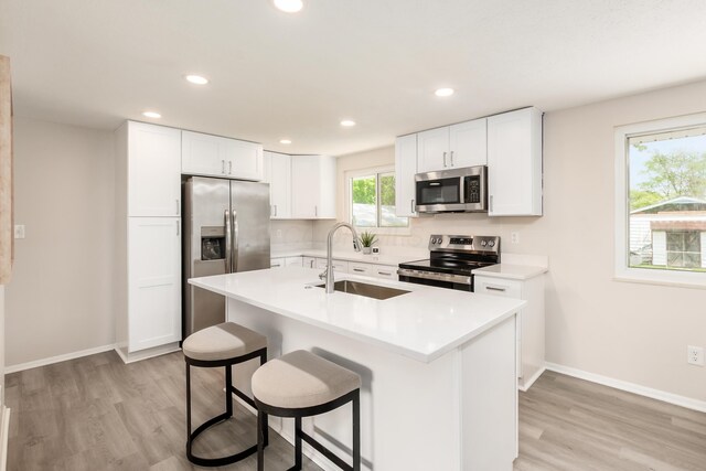2142 Balford Sq W, Columbus, OH 43232 - kitchen featuring stainless steel appliances, light wood-style floors, white cabinetry, recessed lighting, and a kitchen bar