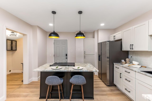 72 Avondale Ave, Columbus, OH 43222 - kitchen with white cabinetry, a kitchen island, a breakfast bar, stainless steel fridge with ice dispenser, and light stone countertops