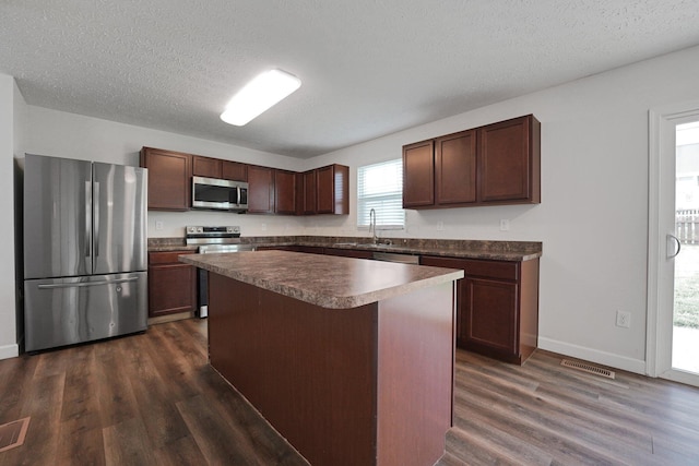 2576 Brook Run Dr, Lancaster, OH 43130 - kitchen featuring stainless steel appliances, dark wood-style flooring, dark countertops, baseboards, and a textured ceiling