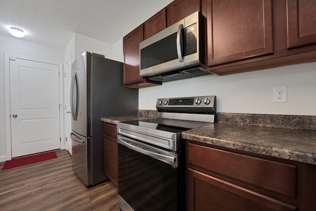 2576 Brook Run Dr, Lancaster, OH 43130 - kitchen featuring stainless steel appliances, dark countertops, dark wood-style flooring, a textured ceiling, and dark brown cabinetry