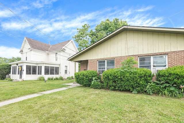 66-64 Eaton St, Delaware, OH 43015 - view of front of home with brick siding, a front yard, and a sunroom