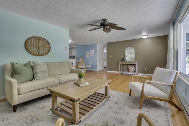 4476 Stiving Rd, Shelby, OH 44875 - living room with light wood-style floors, ceiling fan, a textured ceiling, plenty of natural light, and baseboard heating