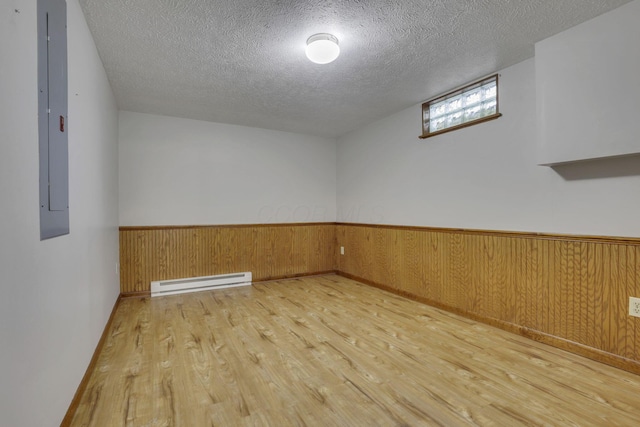 4476 Stiving Rd, Shelby, OH 44875 - unfurnished room with baseboard heating, wood finished floors, a textured ceiling, wainscoting, and electric panel