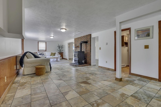 4476 Stiving Rd, Shelby, OH 44875 - living area featuring a wood stove, a baseboard heating unit, a textured ceiling, and light stone finish floors