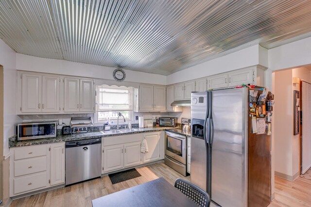4909 Vanlear Rd, Columbus, OH 43229 - kitchen with stainless steel appliances, a sink, light wood-style floors, under cabinet range hood, and white cabinetry