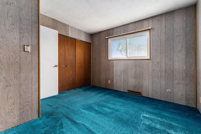 5045 Labelle Dr, Columbus, OH 43232 - unfurnished bedroom featuring carpet floors, a textured ceiling, a closet, and wooden walls