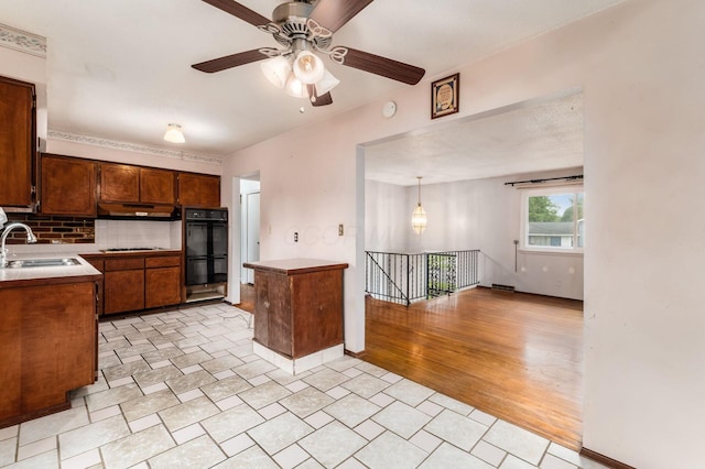 5045 Labelle Dr, Columbus, OH 43232 - kitchen with a sink, under cabinet range hood, tasteful backsplash, a ceiling fan, and light countertops