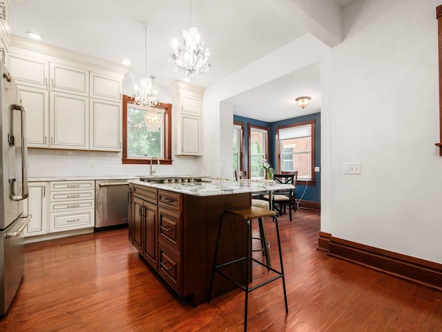 471 W 4th Ave, Columbus, OH 43201 - kitchen featuring appliances with stainless steel finishes, a chandelier, a breakfast bar, baseboards, and backsplash
