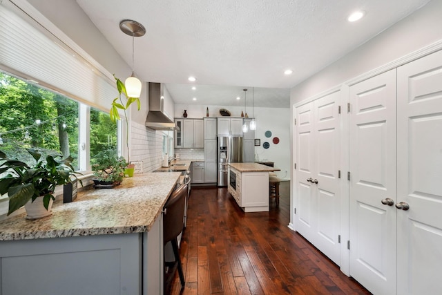 5191 Hialeah Ct, Columbus, OH 43221 - kitchen with wall chimney exhaust hood, stainless steel refrigerator with ice dispenser, gray cabinetry, dark wood-style flooring, and light stone countertops