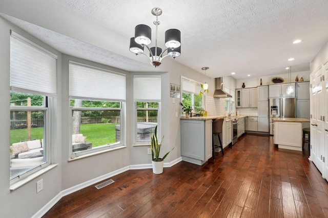 5191 Hialeah Ct, Columbus, OH 43221 - kitchen with wall chimney range hood, a textured ceiling, a chandelier, stainless steel fridge, and dark wood-style floors