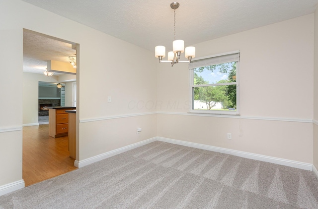 8732 Eastfield Ct, Pickerington, OH 43147 - empty room featuring light carpet, a chandelier, a fireplace, and a textured ceiling