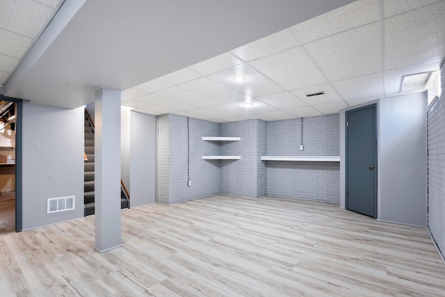 4686 Gilman Rd, Columbus, OH 43228 - finished basement with a paneled ceiling, brick wall, light wood finished floors, and stairs