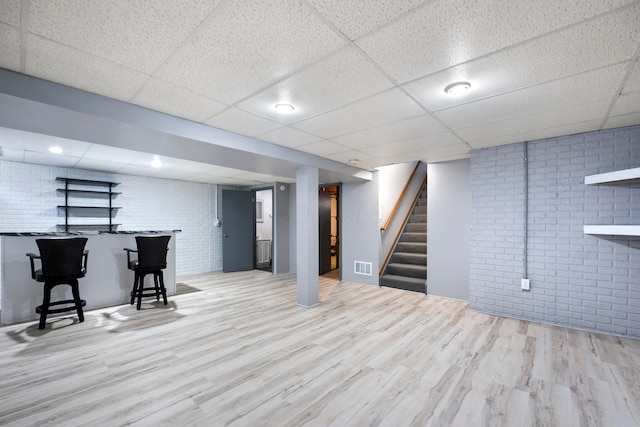 4686 Gilman Rd, Columbus, OH 43228 - finished basement featuring brick wall, wood finished floors, a drop ceiling, and stairs