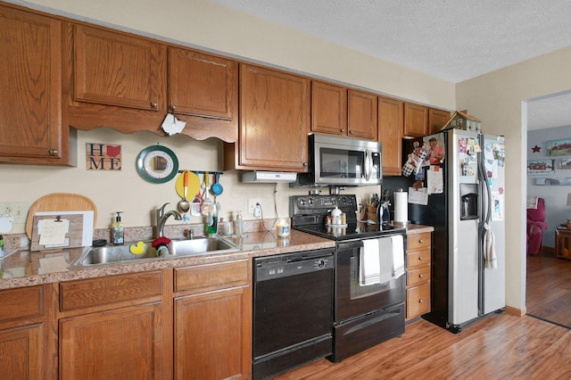 452 Samantha Cir Unit 10, London, OH 43140 - kitchen featuring black appliances, a sink, light wood-style flooring, brown cabinets, and light countertops
