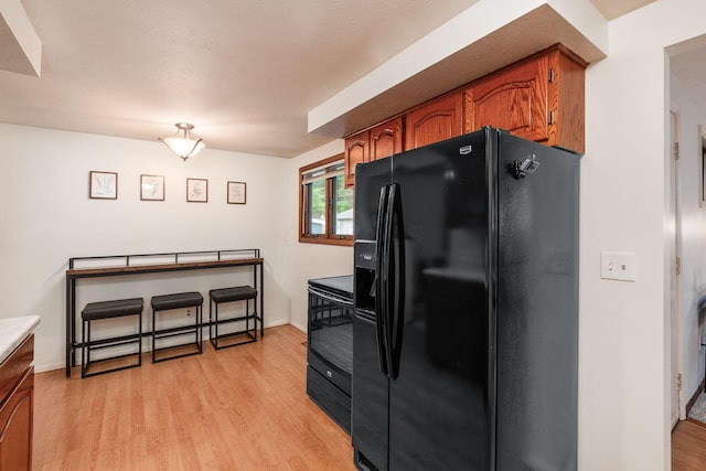815 Savannah Dr, Columbus, OH 43228 - kitchen featuring black fridge with ice dispenser, electric range oven, light wood-type flooring, brown cabinets, and light countertops