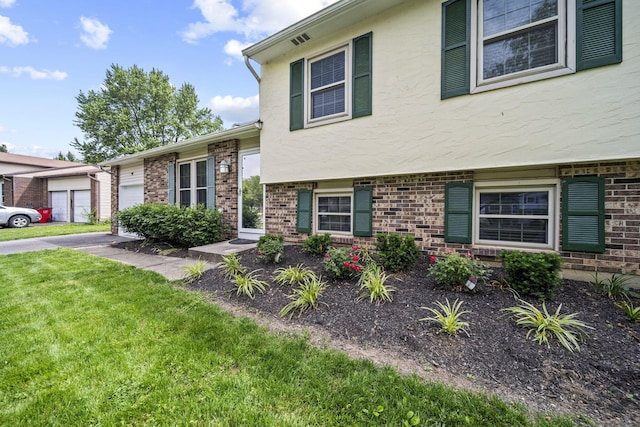 4150 Demorest Rd, Grove City, OH 43123 - view of front facade with stucco siding, brick siding, a front lawn, and a garage