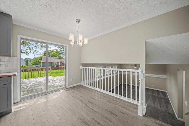 4150 Demorest Rd, Grove City, OH 43123 - unfurnished dining area featuring wood finished floors, crown molding, a chandelier, a textured ceiling, and baseboards