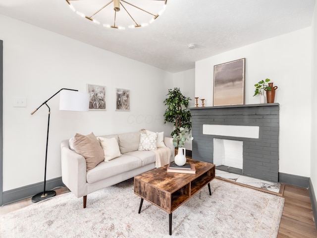 1432 Cordell Ave, Columbus, OH 43211 - living room with wood finished floors, a brick fireplace, and a chandelier