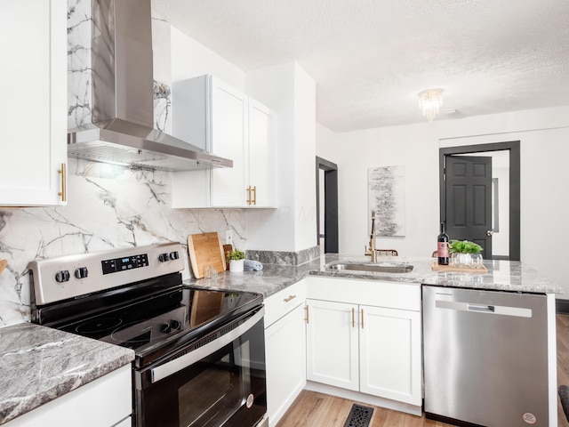 1432 Cordell Ave, Columbus, OH 43211 - kitchen with appliances with stainless steel finishes, wall chimney range hood, a peninsula, light stone countertops, and white cabinets