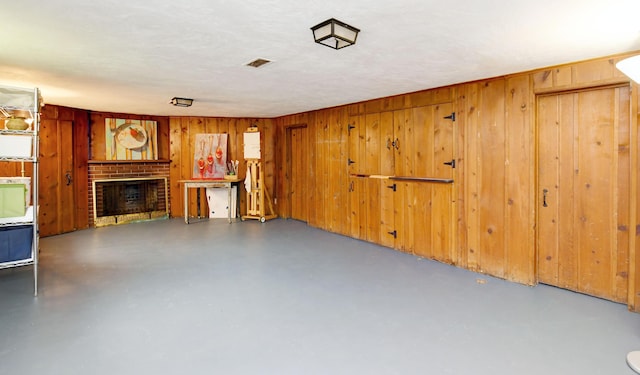 259 N Stanwood Rd, Columbus, OH 43209 - unfurnished living room featuring concrete flooring, a brick fireplace, and wood walls