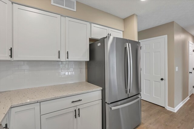 4583 Hunting Creek Dr, Grove City, OH 43123 - kitchen featuring freestanding refrigerator, white cabinetry, decorative backsplash, light wood-style flooring, and light stone countertops