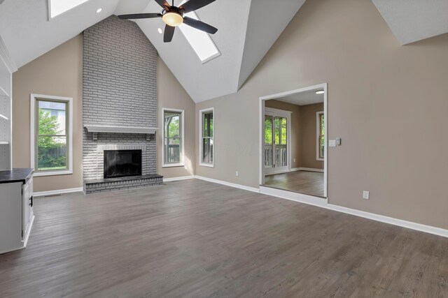 4583 Hunting Creek Dr, Grove City, OH 43123 - unfurnished living room with a ceiling fan, a skylight, a brick fireplace, high vaulted ceiling, and dark wood-type flooring