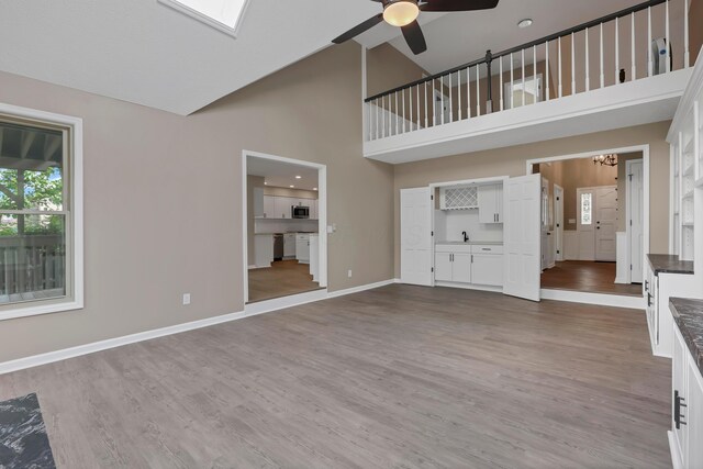 4583 Hunting Creek Dr, Grove City, OH 43123 - unfurnished living room featuring ceiling fan, high vaulted ceiling, wood finished floors, a chandelier, and baseboards